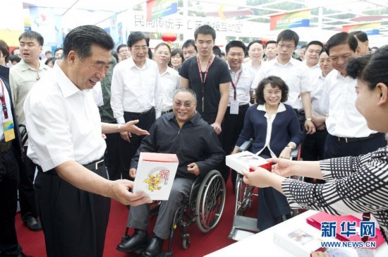 5月20日，是第22个全国助残日。中共中央政治局委员、国务院副总理、国务院残疾人工作委员会主任回良玉等来到北京市地坛公园观看北京市残疾人优秀文化成果展示，并向全国8500万残疾人和广大残疾人家属表示亲切问候和良好祝愿。这是回良玉观看残疾人制作的工艺品成果展示。新华社记者王晔摄