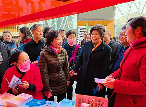 图为张义珍在昆明市西山区人社局开展的“就业援助月”活动现场，与工作人员、援助对象亲切交流，询问援助流程和援助政策落实情况。