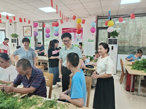 图为黄埔区残联周挹渊副理事长（右四）和工疗学员交谈